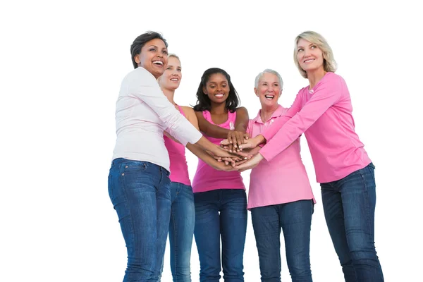 Mujeres que usan cintas de cáncer de mama con las manos juntas y sonrisas — Foto de Stock