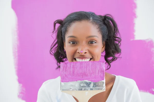 Young woman holding paintbrush with paint on her nose — Stock Photo, Image