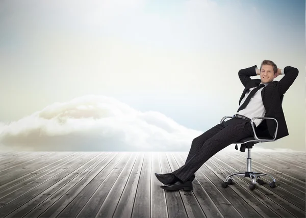 Smiling businessman sitting in a swivel chair — Stock Photo, Image