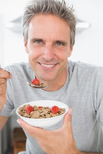 Happy man eating cereal for breakfast — Stock Photo, Image