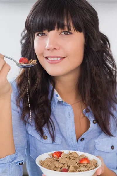 Lächelnde Brünette mit einer Schüssel Müsli und Obst — Stockfoto