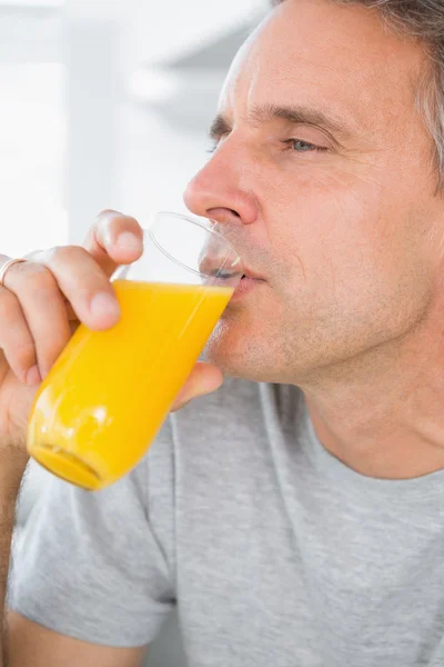 Περιεχομένου άνθρωπος πίνοντας χυμό πορτοκαλιού στην κουζίνα — Φωτογραφία Αρχείου