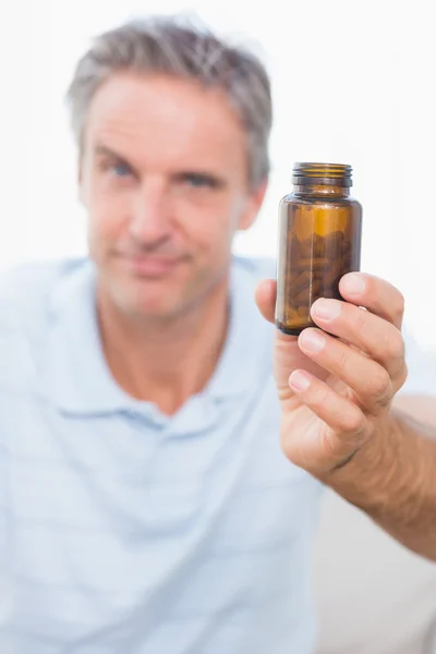 Человек показывает бутылку с таблетками на камеру — стоковое фото