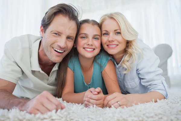 Retrato de una niña y sus padres acostados en una alfombra —  Fotos de Stock