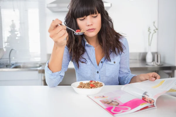 Bella bruna con cereali e rivista di lettura — Foto Stock