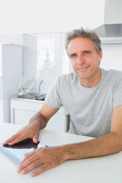 Hombre alegre usando la tableta PC en la cocina —  Fotos de Stock