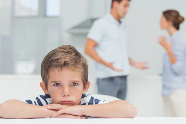 Ragazzo triste con le braccia incrociate mentre i genitori litigano — Foto Stock