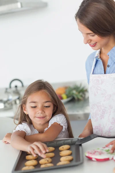 Menina pegando um biscoito de uma assadeira — Fotografia de Stock