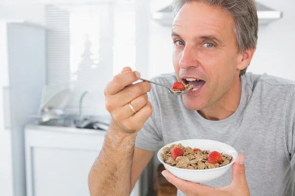 Homem feliz comendo cereais para o café da manhã na cozinha — Fotografia de Stock