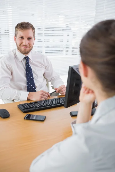 Affärsman som ler mot kameran på hans skrivbord — Stockfoto