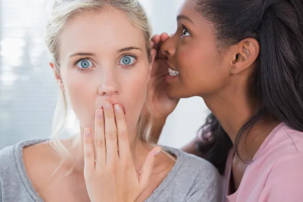 Pretty woman whispering secret to her blonde friend — Stock Photo, Image