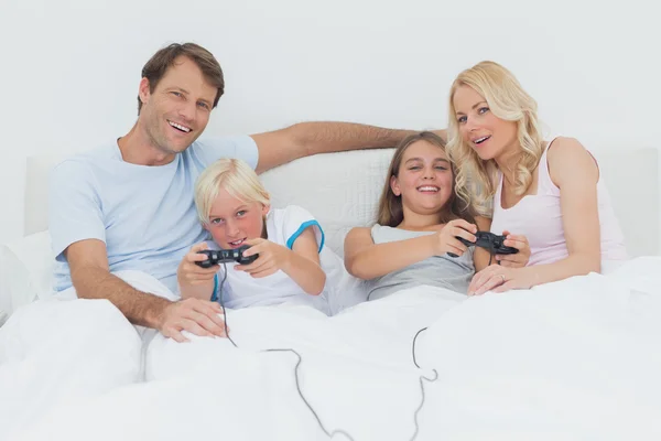 Família jogando jogos de vídeo na cama — Fotografia de Stock