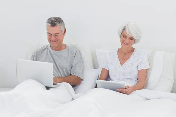 Uomo maturo utilizzando un computer portatile a letto — Foto Stock