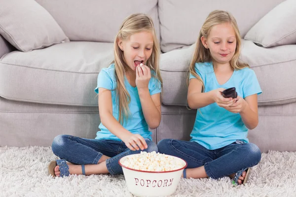 Twins eating popcorn and watching television — Stock Photo, Image