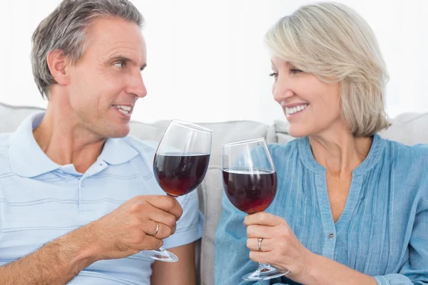Coppia di brindisi con vino rosso sul divano — Foto Stock