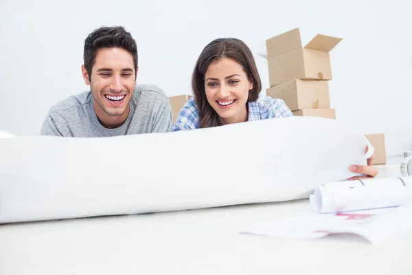 Couple lying on the floor and holding a house plan — Stock Photo, Image