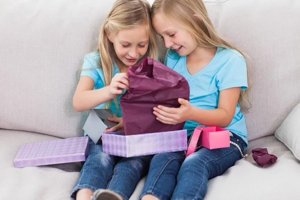 Gemelos jóvenes desenvolviendo regalo de cumpleaños sentado en un sofá —  Fotos de Stock