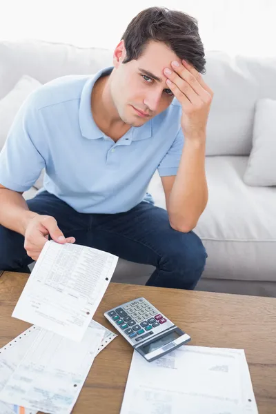 Fearful man doing his accounts with a calculator — Stock Photo, Image