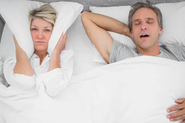 Man snoring loudly as partner blocks her ears — Stock Photo, Image