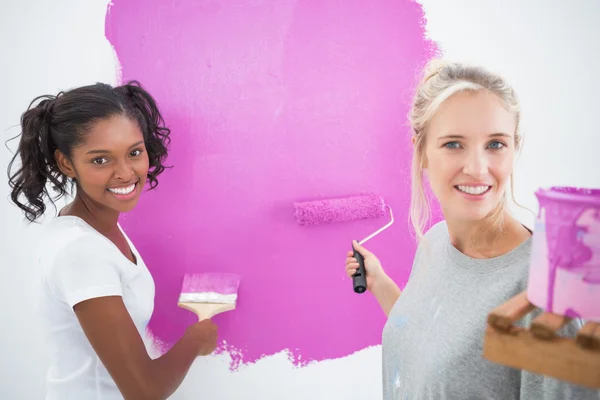 Sorrindo housemates pintura parede rosa — Fotografia de Stock