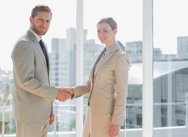 Business people shaking hands and smiling at camera — Stock Photo, Image