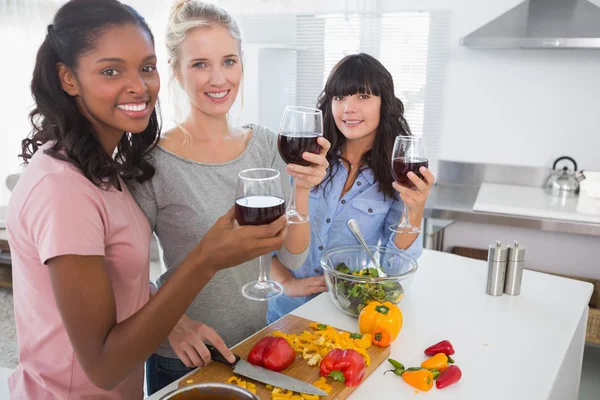 Amici allegri che preparano un pasto insieme e bevono vino rosso — Foto Stock