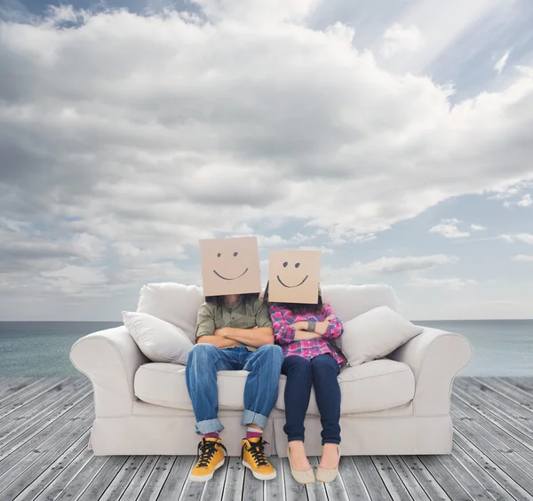 Couple sitting on couch with cardboard over their head — Stock Photo, Image