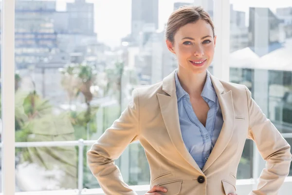 Pretty businesswoman smiling at camera with hands on hips — Stock Photo, Image