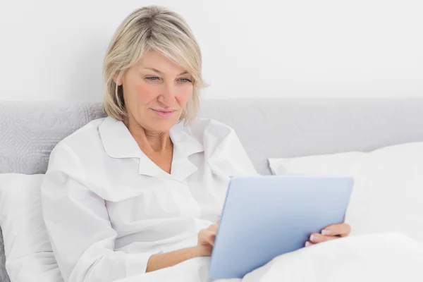 Mujer feliz sentada en la cama usando tableta pc — Foto de Stock