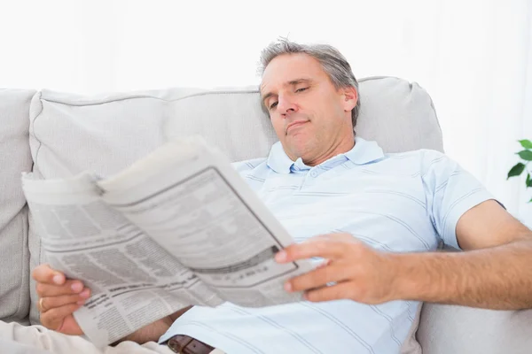 Homem lendo o jornal no sofá — Fotografia de Stock