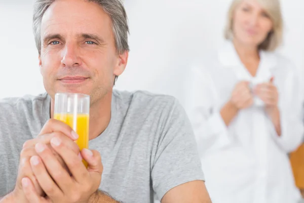 Feliz hombre bebiendo jugo de naranja en la cocina — Foto de Stock