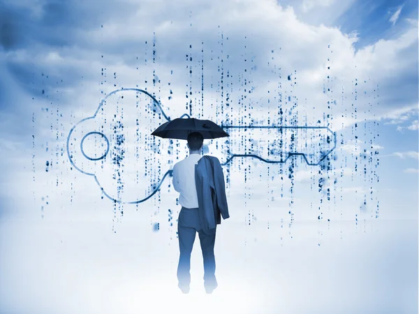 Businessman with an umbrella looking at a giant key — Stock Photo, Image