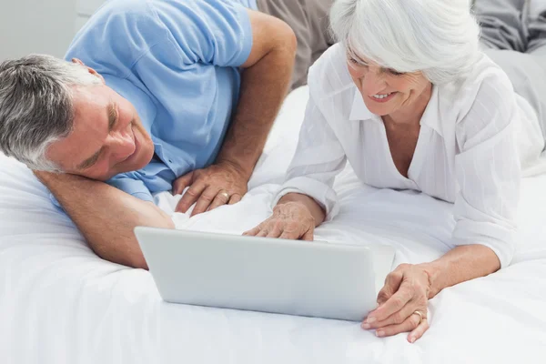 Pareja alegre usando un portátil en la cama — Foto de Stock