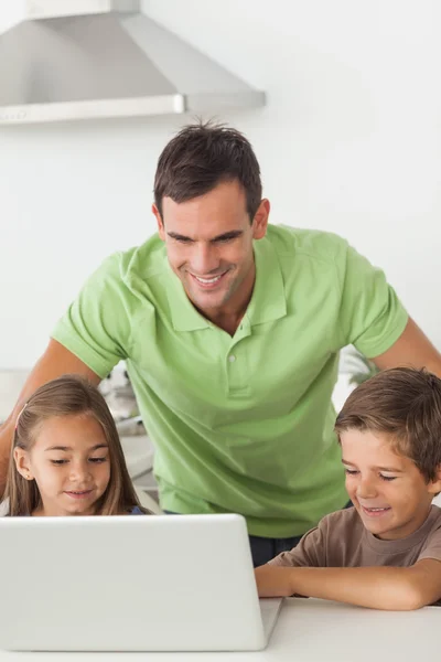 Homem e seus filhos usando um laptop juntos — Fotografia de Stock