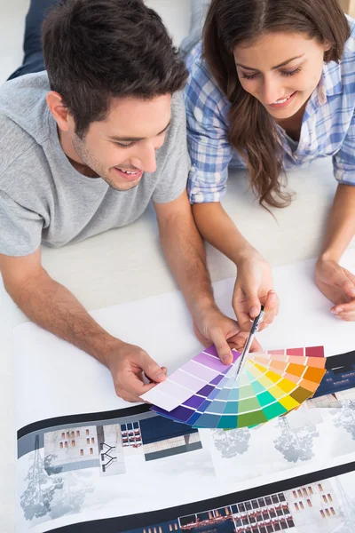 Pareja mirando una carta de colores para decorar su casa — Foto de Stock