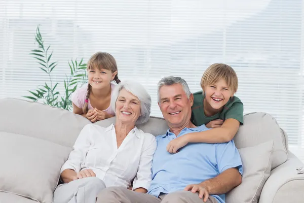 Grandchildren and grandparents sitting on couch — Stock Photo, Image