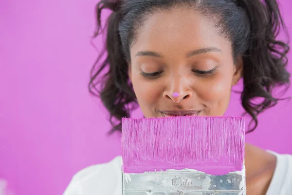 Cheerful woman holding paintbrush with paint on her nose — Stock Photo, Image