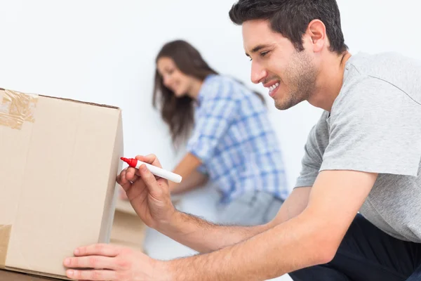 Hombre escribiendo con un marcador rojo en una caja en movimiento — Foto de Stock