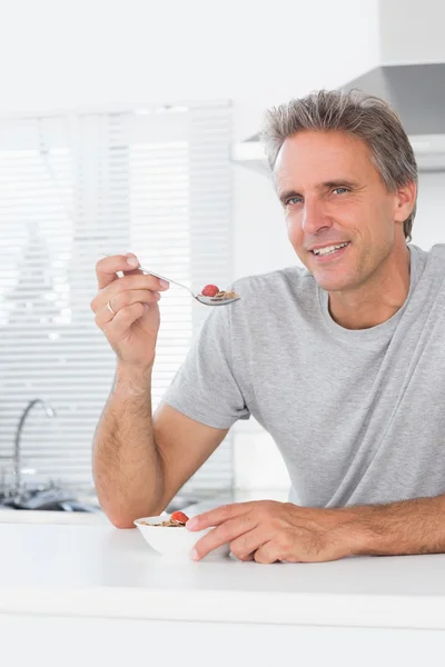 Vrolijke man met granen voor het ontbijt in de keuken — Stockfoto