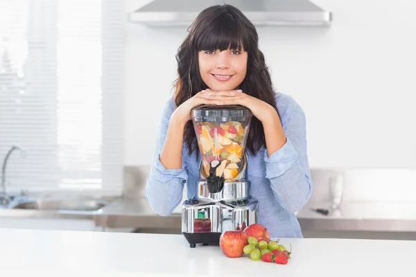 Bella bruna appoggiata al suo spremiagrumi pieno di frutta — Foto Stock