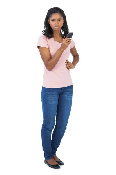 Ernstige vrouw met mobiele telefoon met haar hand op heup — Stockfoto