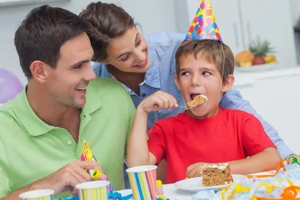 Little boy eating a birthday cake with parents — Stock Photo, Image