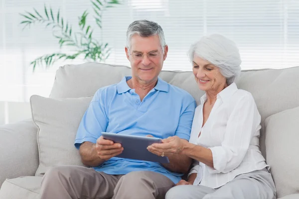 Paar met behulp van een tablet zittend op de Bank — Stockfoto