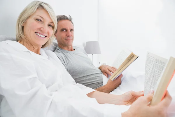 Happy couple reading books in bed — Stock Photo, Image