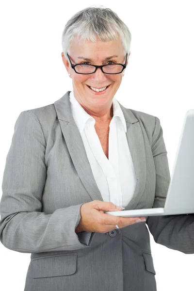 Mujer de negocios sonriente con gafas sosteniendo su portátil — Foto de Stock