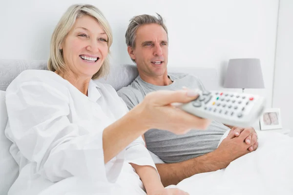 Lyckliga paret tittar på tv i sängen — Stockfoto