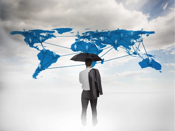 Empresário com um guarda-chuva olhando para um mapa do mundo — Fotografia de Stock