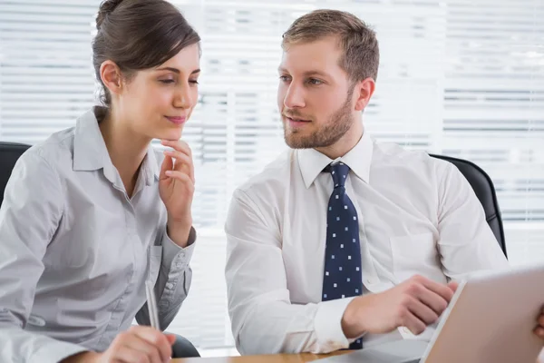 Zakenman wijzend op laptop met collega — Stockfoto