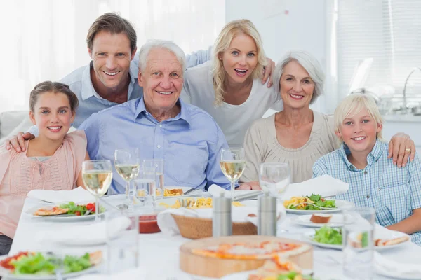 Расширенная семья улыбается семье за ужином — стоковое фото
