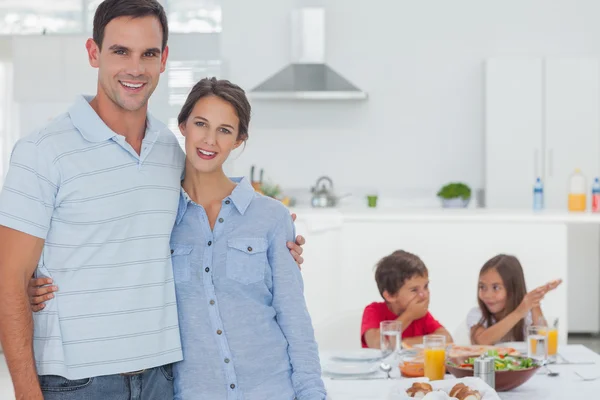 Couple standing in front of children at the table Stock Photo